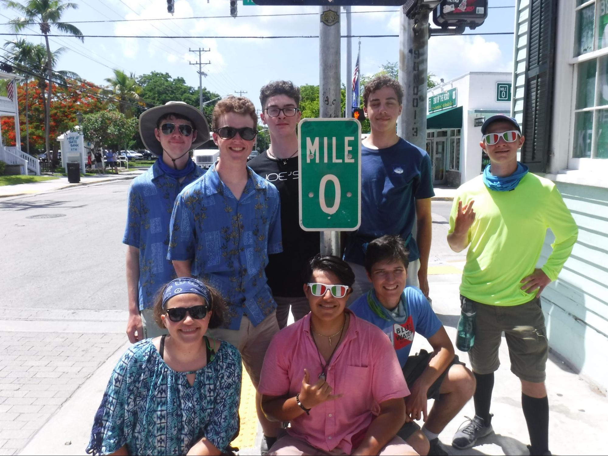Sarah poses with friends at a sign labeled "Mile 0"