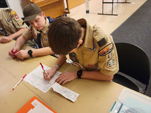 Two Arrowmen at a unit visitation double-check their counts of unit election ballots to ensure accuracy and correctness in the final report of who was elected.